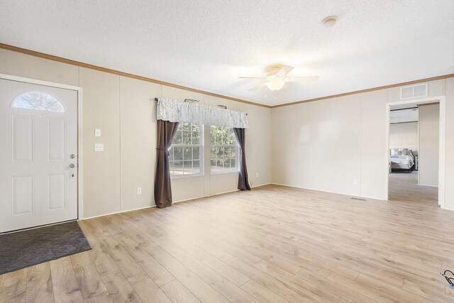 foyer entrance with visible vents, a ceiling fan, a textured ceiling, crown molding, and light wood-style flooring