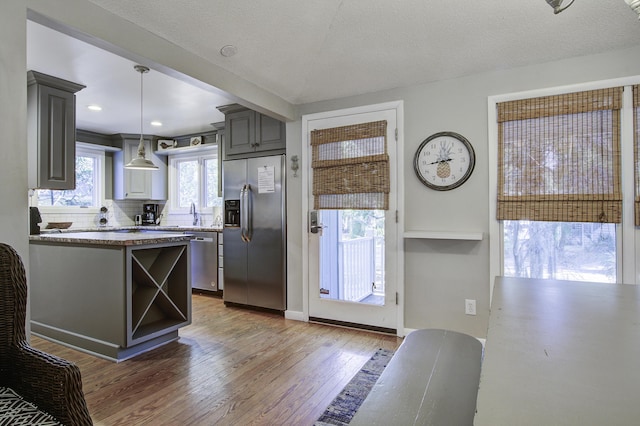 kitchen featuring gray cabinetry, stainless steel appliances, dark hardwood / wood-style flooring, pendant lighting, and a textured ceiling