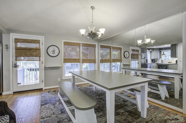 dining room with wood-type flooring, a textured ceiling, and an inviting chandelier