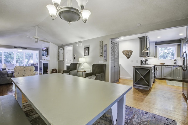 kitchen with decorative backsplash, a center island, ceiling fan with notable chandelier, and gray cabinetry