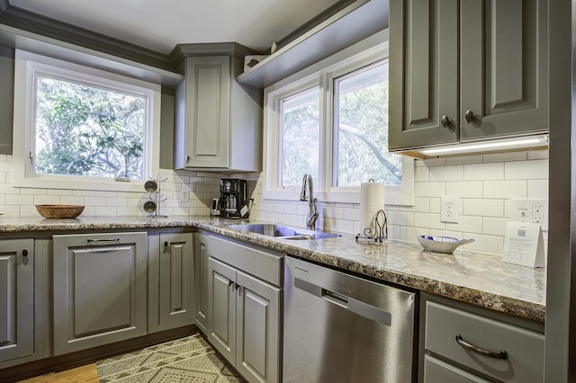 kitchen featuring gray cabinets, stainless steel dishwasher, dark stone countertops, and sink