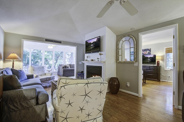 living room featuring hardwood / wood-style flooring, ceiling fan, and vaulted ceiling