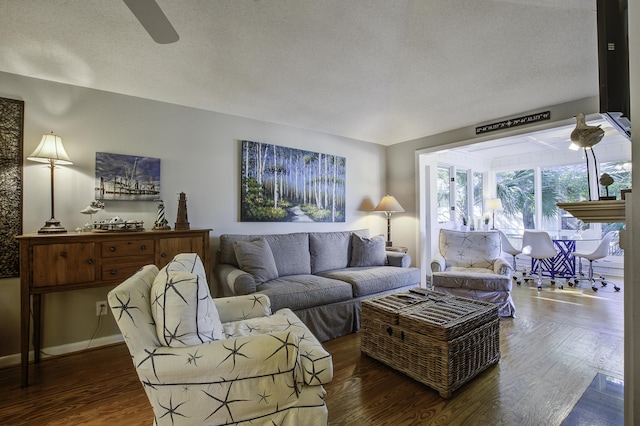 living room featuring a textured ceiling, ceiling fan, and dark wood-type flooring