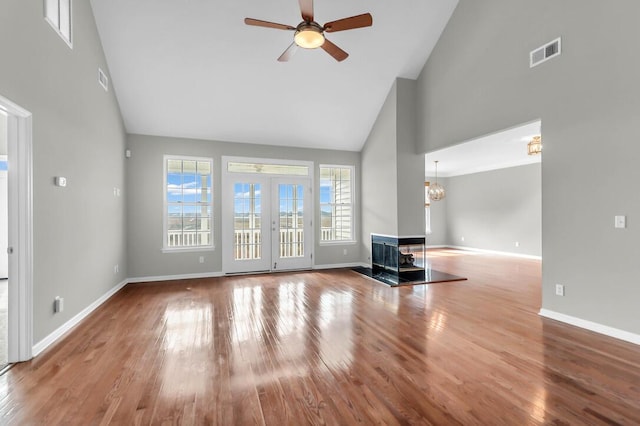 unfurnished living room featuring hardwood / wood-style floors, ceiling fan with notable chandelier, and high vaulted ceiling