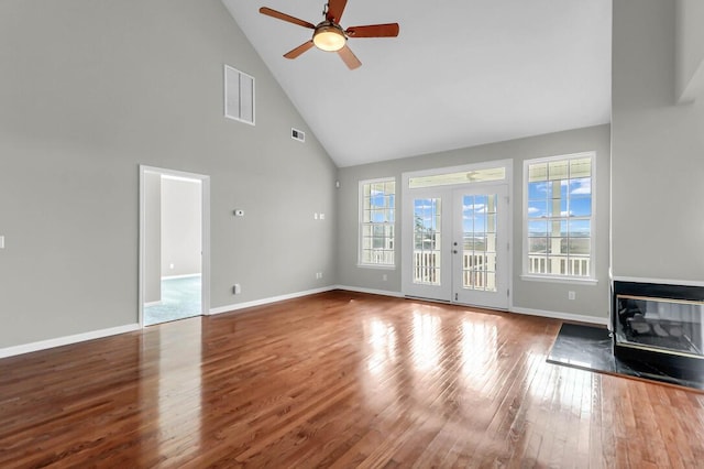 unfurnished living room featuring hardwood / wood-style flooring, ceiling fan, high vaulted ceiling, and french doors