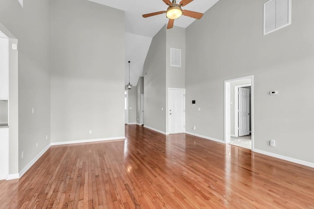 unfurnished living room with hardwood / wood-style floors, high vaulted ceiling, and ceiling fan