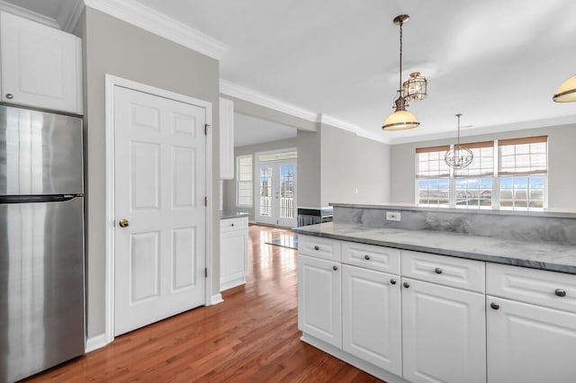 kitchen with white cabinetry, crown molding, stainless steel fridge, and a wealth of natural light