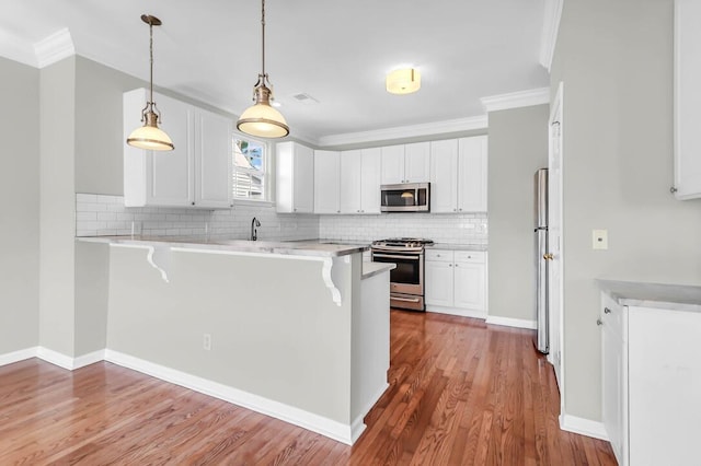 kitchen featuring appliances with stainless steel finishes, white cabinets, backsplash, and kitchen peninsula