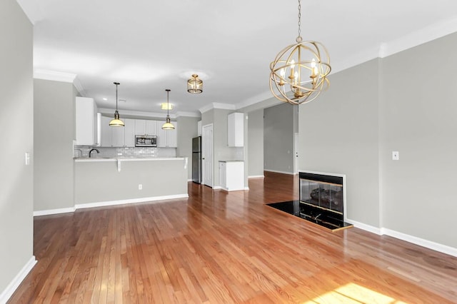 unfurnished living room featuring an inviting chandelier, wood-type flooring, and ornamental molding