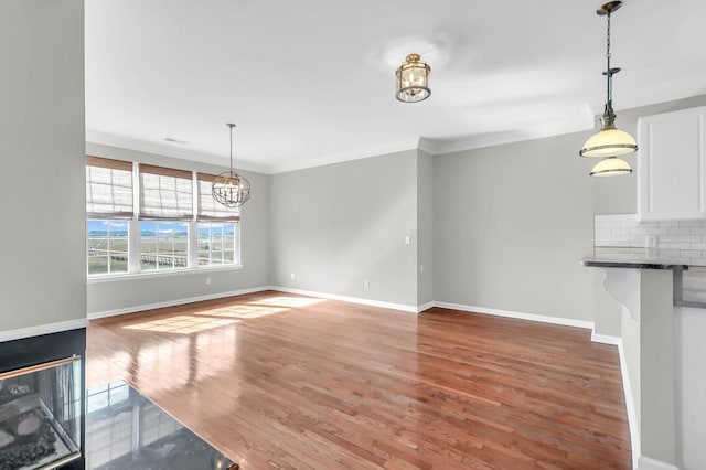 unfurnished living room featuring crown molding, a chandelier, and hardwood / wood-style floors