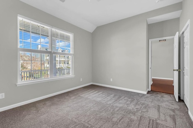 carpeted spare room with vaulted ceiling