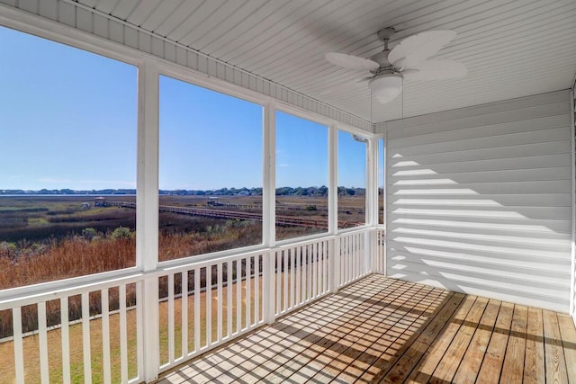 unfurnished sunroom with ceiling fan and a rural view