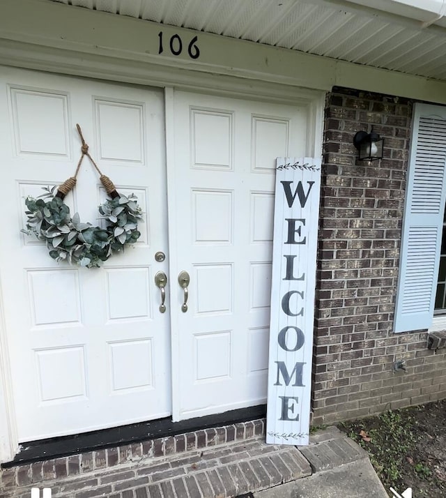 property entrance featuring a garage and brick siding