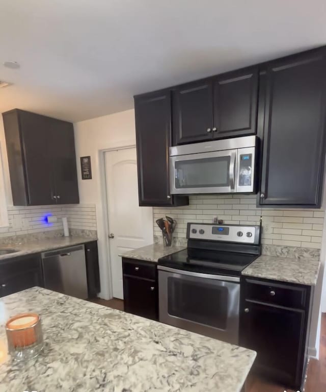 kitchen featuring light stone counters, decorative backsplash, and appliances with stainless steel finishes