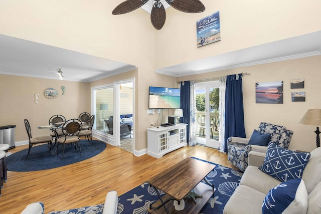 living area featuring ornamental molding, a ceiling fan, baseboards, and wood finished floors