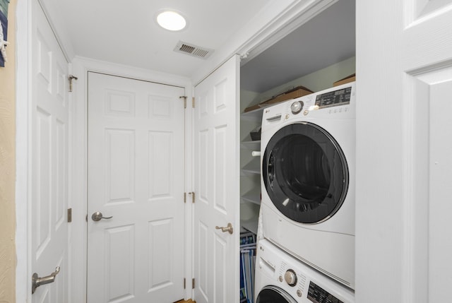 clothes washing area featuring laundry area, visible vents, and stacked washing maching and dryer