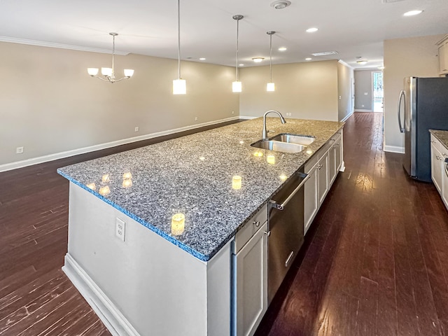 kitchen featuring sink, appliances with stainless steel finishes, an island with sink, and pendant lighting