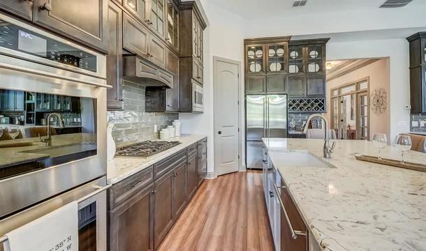 kitchen featuring dark brown cabinetry, backsplash, appliances with stainless steel finishes, custom range hood, and hardwood / wood-style flooring