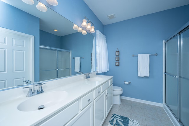 full bath with double vanity, a shower stall, baseboards, and a sink