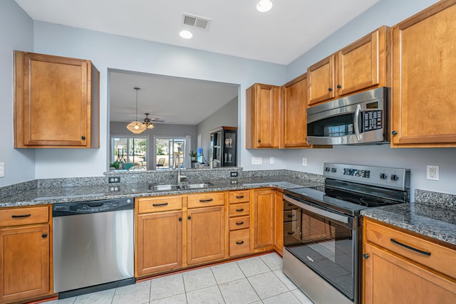 kitchen with dark stone countertops, visible vents, a sink, stainless steel appliances, and brown cabinets