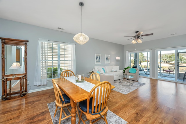 dining room featuring ceiling fan, visible vents, baseboards, and wood finished floors