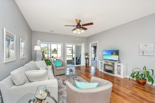 living area featuring visible vents, baseboards, ceiling fan, and wood finished floors