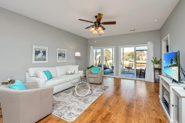 living area featuring light wood finished floors, visible vents, and a ceiling fan