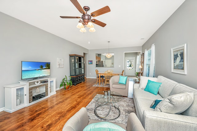 living area with a ceiling fan, baseboards, and wood finished floors