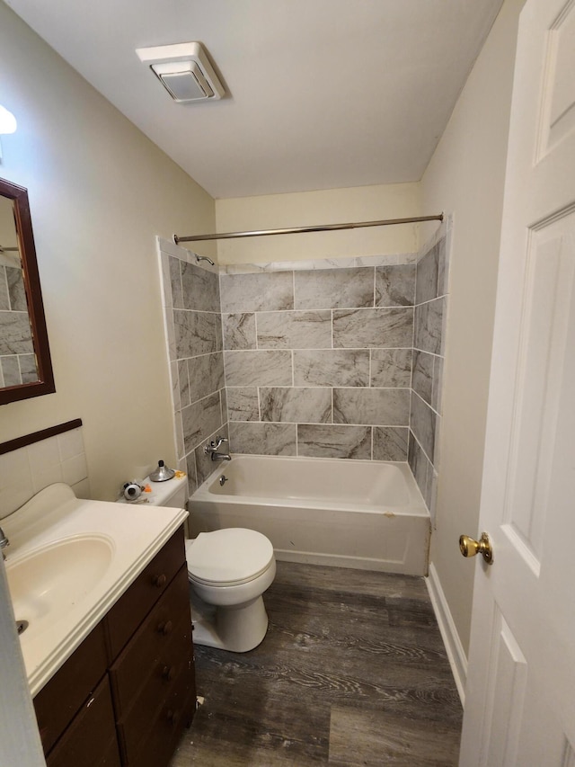 full bathroom featuring vanity, hardwood / wood-style flooring, tiled shower / bath, and toilet