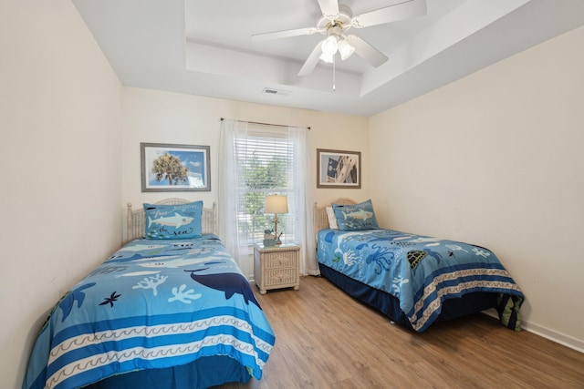 bedroom featuring wood-type flooring, ceiling fan, and a tray ceiling