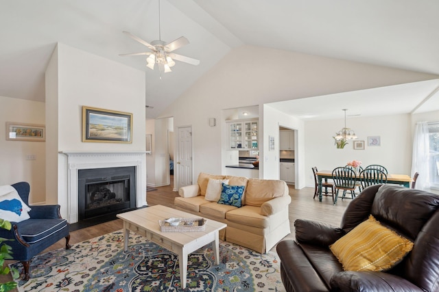 living room with hardwood / wood-style flooring, ceiling fan with notable chandelier, and high vaulted ceiling