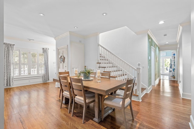 dining room featuring baseboards, crown molding, stairway, and wood finished floors