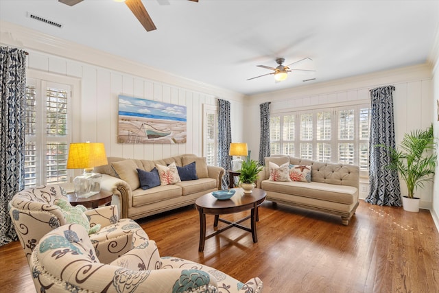 living room with a ceiling fan, visible vents, crown molding, and wood finished floors