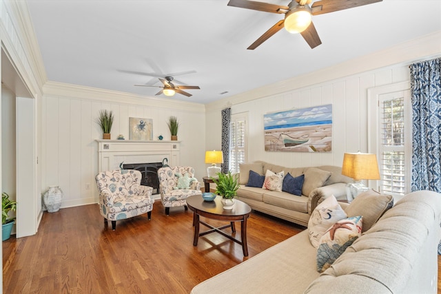 living area featuring crown molding, a fireplace, a ceiling fan, and wood finished floors