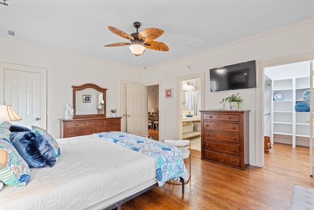 bedroom with visible vents, a walk in closet, crown molding, light wood-type flooring, and a closet