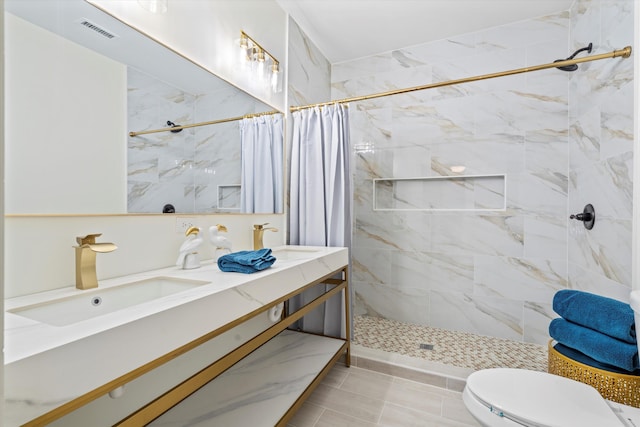 full bathroom with toilet, tiled shower, a sink, and visible vents