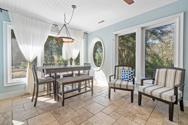 dining area featuring a healthy amount of sunlight, visible vents, crown molding, and stone tile floors