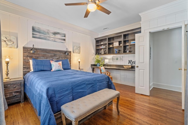 bedroom featuring ceiling fan, visible vents, crown molding, and wood finished floors