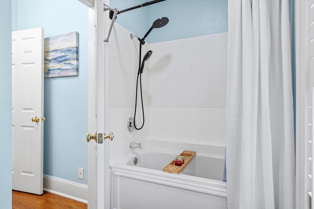 full bathroom with wood finished floors, shower / bath combo with shower curtain, and baseboards