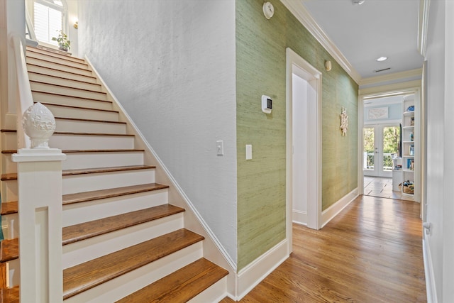 staircase featuring baseboards, french doors, wood finished floors, and crown molding