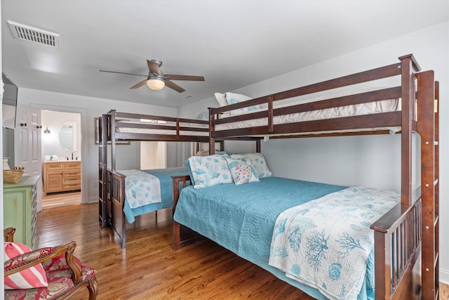 bedroom with connected bathroom, visible vents, ceiling fan, and wood finished floors