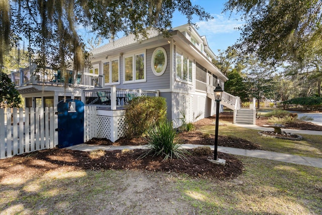 view of front of home featuring a deck, fence, and stairway