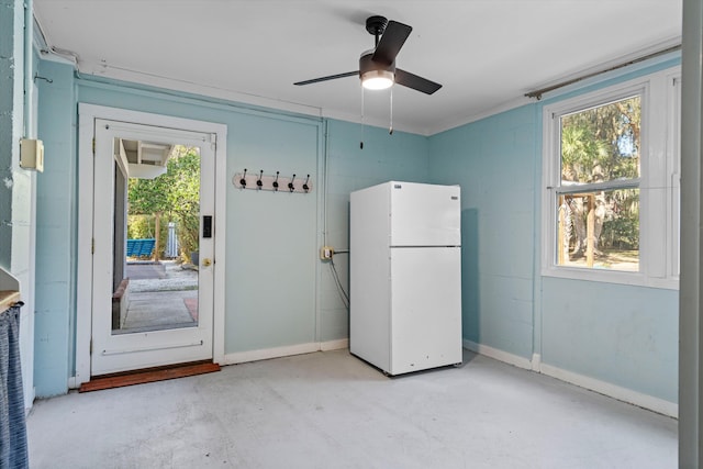 interior space featuring concrete block wall, unfinished concrete floors, baseboards, and a wealth of natural light