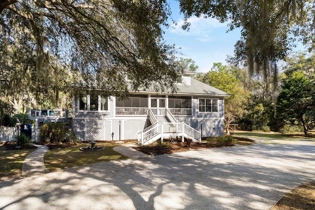 view of front of property with a sunroom, driveway, and stairs