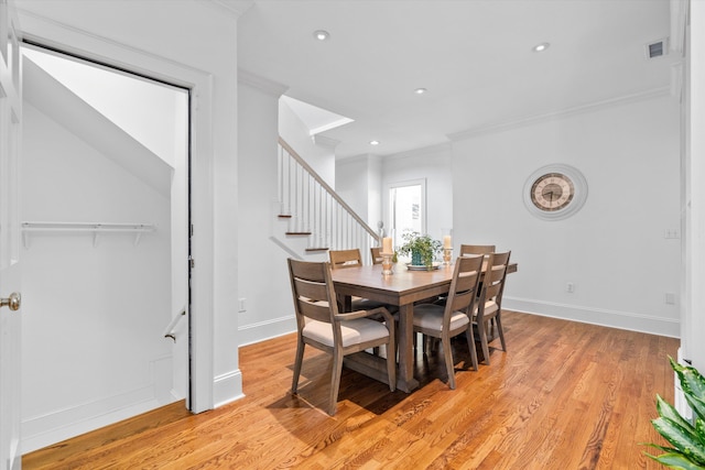 dining space with light wood finished floors, baseboards, visible vents, stairs, and crown molding