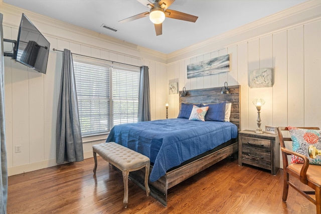 bedroom featuring ceiling fan, wood finished floors, visible vents, baseboards, and crown molding