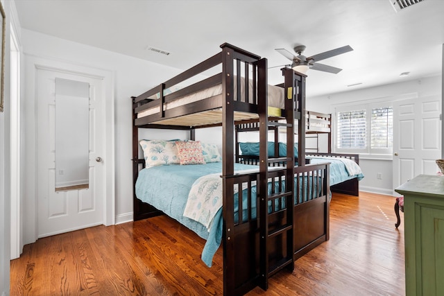 bedroom with wood finished floors, visible vents, and baseboards