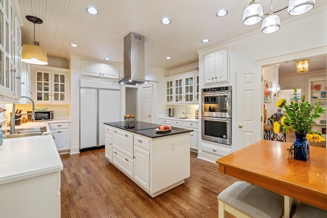 kitchen with paneled built in fridge, a kitchen island, island exhaust hood, stainless steel double oven, and a sink