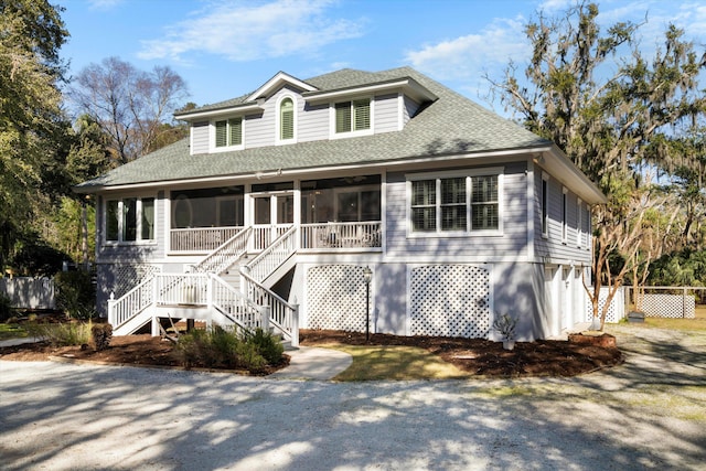 view of front of home featuring stairs, a shingled roof, a sunroom, and a garage