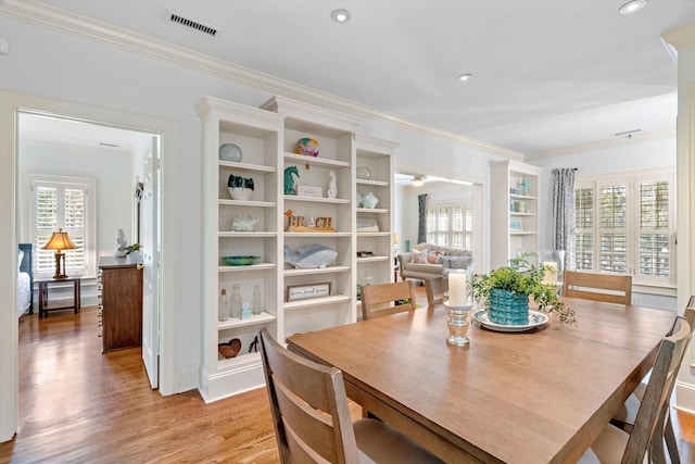 dining room featuring visible vents, a healthy amount of sunlight, crown molding, and light wood-style flooring